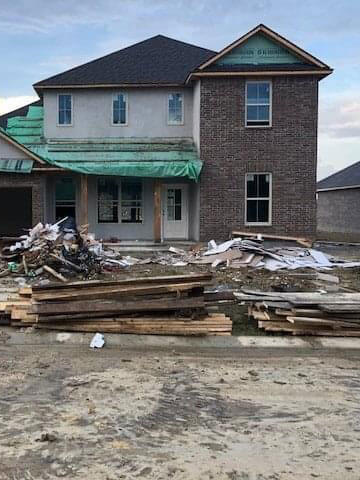 House with a ton of construction debris on front lawn